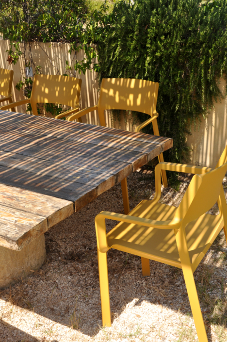 Dining area with yellow chairs in the shade at Mezzao Apartments, Kefalonia.